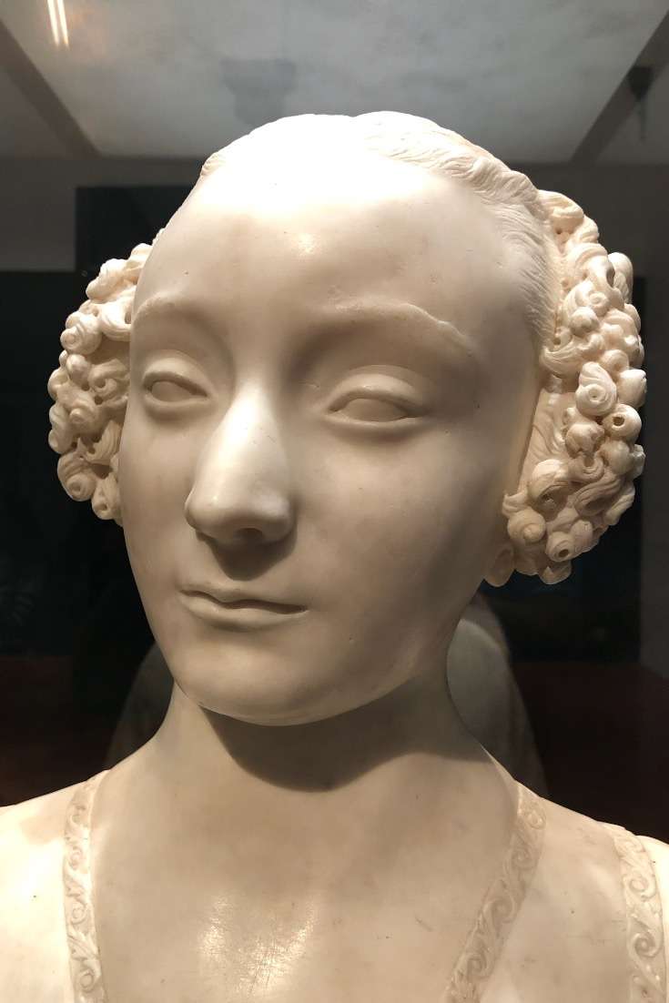 White sculpture of a man with curly hair at the Uffizi Museum in Florence